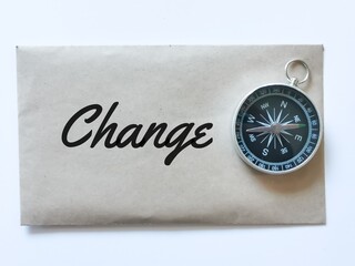 Text change written on brown envelope with magnetic compass.