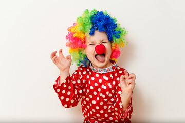 Hilarious five-year-old boy dances in clown costume and wig on white background