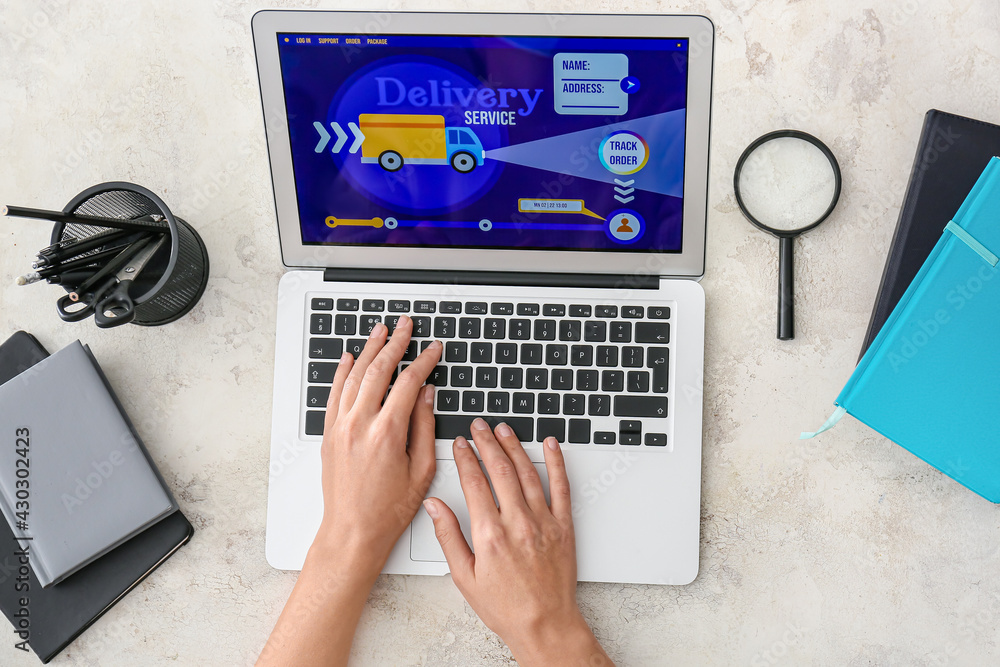 Poster woman using laptop with open page of delivery service application at table