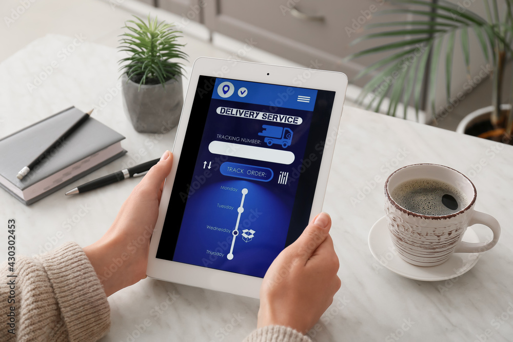 Poster woman holding tablet computer with open page of delivery service application at home