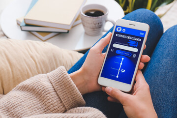 Woman holding mobile phone with open page of delivery service application at home