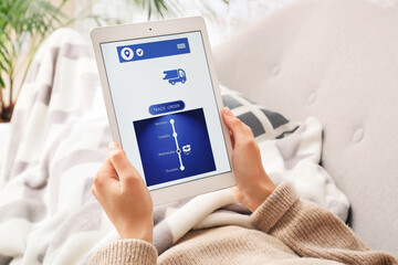 Woman holding tablet computer with open page of delivery service application at home