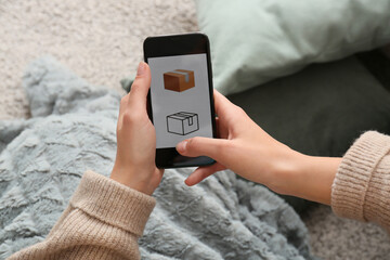 Woman holding mobile phone with open page of delivery service application at home