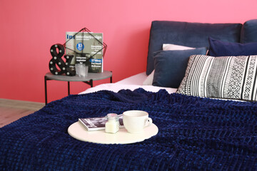 Tray with cup of coffee on bed