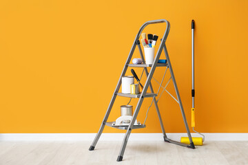 Ladder with cans of paints and tools near color wall © Pixel-Shot