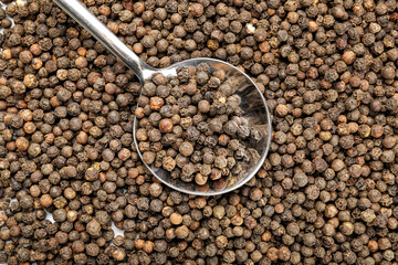 Spoon and peppercorns as background