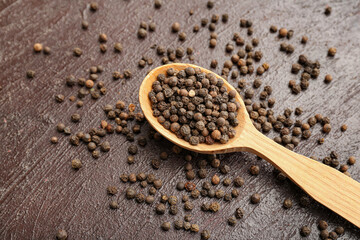 Spoon with peppercorns on dark background