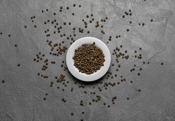 Plate with peppercorns on dark background