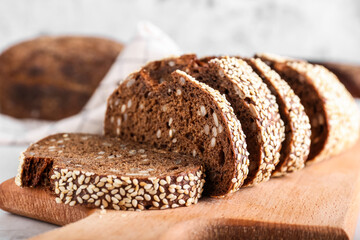 Board with fresh cut bread on light background, closeup