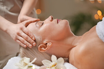 Obraz na płótnie Canvas Mature woman receiving face massage in beauty salon