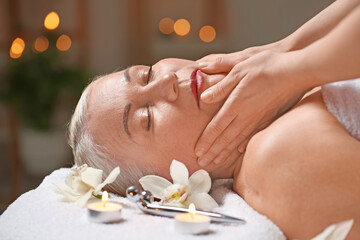 Obraz na płótnie Canvas Mature woman receiving face massage in beauty salon
