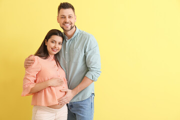 Beautiful pregnant couple on color background