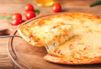 Taking slice of tasty pizza from board on wooden background