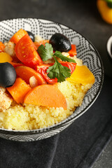 Bowl with couscous and vegetables on dark background