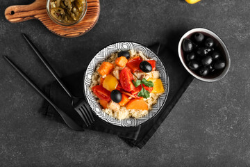 Bowl with couscous and vegetables on dark background