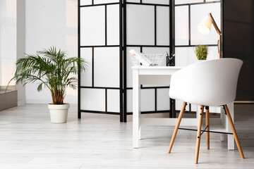 Interior of room with comfortable workplace and folding screen