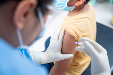 Fototapeta premium Close up Doctor making a vaccination in the shoulder of patient boy or child person, coronavirus,covid-19 vaccine disease preparing for human clinical trials vaccination shot, Injection on Arm