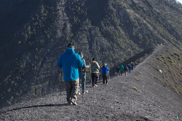 group of hikers walking in a row on the trail with a view of the Acatenango Volcano and the camping...