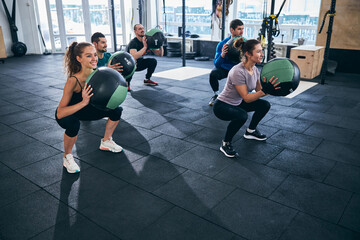 Five athletes exercising with stability balls indoors