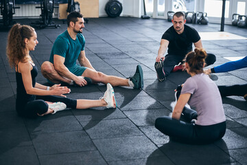 Fitness coach and his clients performing the seated forward bend