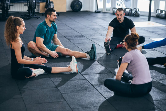 Fitness coach and his clients performing the seated forward bend