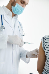 male doctor in a white coat injections in the arm with a vaccine coronavirus