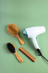 Eco Hair styling concept. Ionic hairdryer with diffuser , different natural wood brushes on green background.