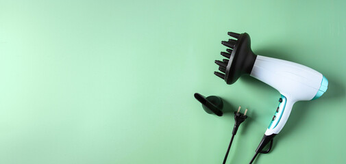 Modern hairdryer with diffuser on green large background  for banner. Hair care and styling concept. Copy space