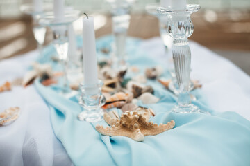 Stylish design of the wedding table in a nautical style. The decor is made of candles, shells and...