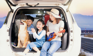 Pet lover. Asian family on the car. Mom and Child are playing music on a van with a beautiful view. Travel to Mount Fuji in Nagoya Prefecture in Japan.
