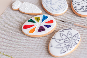 Easter egg biscuit with gray pattern on white glaze and honey cake with a palette of food coloring to paint with a brush