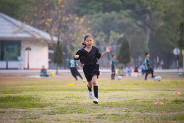 Asian child girl making funny face and running with happiness in the soccer field. Child is happy after win in game. Kid sport recreation concept. © pingpao