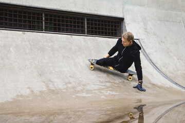 Young handicapped guy with a longboard in a skatepark