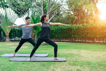 Young Asian couple man and woman practicing yoga in the garden. Summer morning