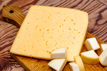 one large and several small pieces of cheese on a cutting board