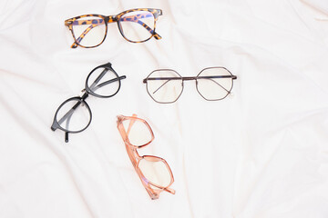 multiple eyes glasses on white crumpled fabric copy space top view
