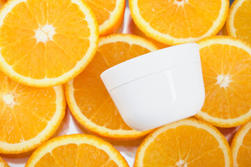 white cream jar on a background of sliced oranges, face and body cream with the addition of orange oil concept, mock up, no label