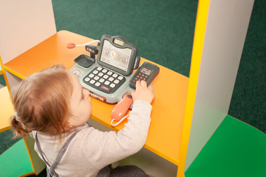 A Two-year-old Girl Plays With Toys In The Playroom. Development Centre, Kindergarten Cash Register Top View