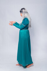 Naklejka premium Full length portrait of a princess in a medieval, fantasy, turquoise dress with ash hair and a silver crown, posing isolated on a white background. 