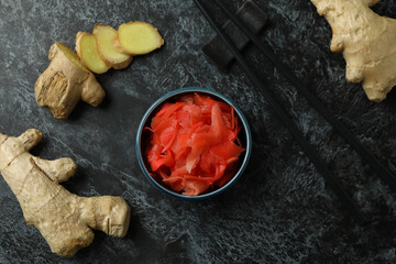 Bowl with red pickled ginger and chopsticks on black smokey background