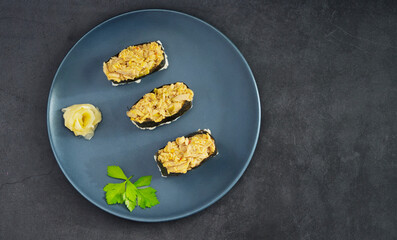 Delicious tuna sushi rolls with ginger on a dark blue plate, black background