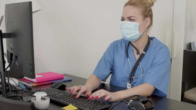 Medical practitioner in mask using computer
