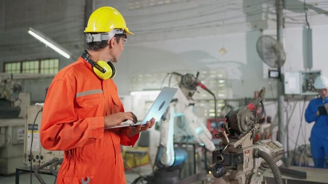 Engineer worker check and control robotic arm machine by using laptop in the intelligent factory. Welding robotic and digital manufacturing operation. Safety workplace. Industrial and technology