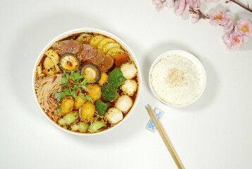 Hot pot is also called Malatang, containing ingredients such as mushrooms, ham, vegetables. Rice, a pair of chopsticks on white board, top view