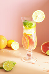Cocktail, yellow and green lemon, mint and blood orange, pink background