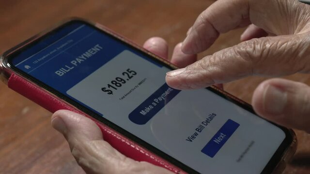 Elderly woman confused and  trying to pay bill on cellphone
