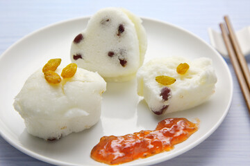 Three rice cakes with red dates and raisins, and sweet sauce in a white plate. Southern Chinese snack