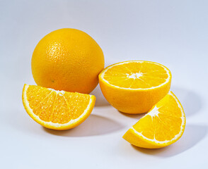 Close-up oranges, one cut into three pieces, fresh fruit flesh, white background