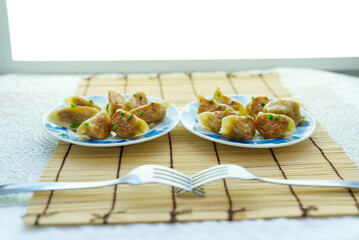 Two golden fried buns and two forks on a sushi mat, depth of field