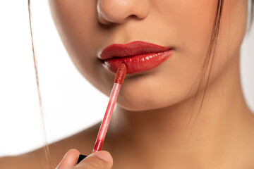 closeup of a young beautiful woman applies lip gloss